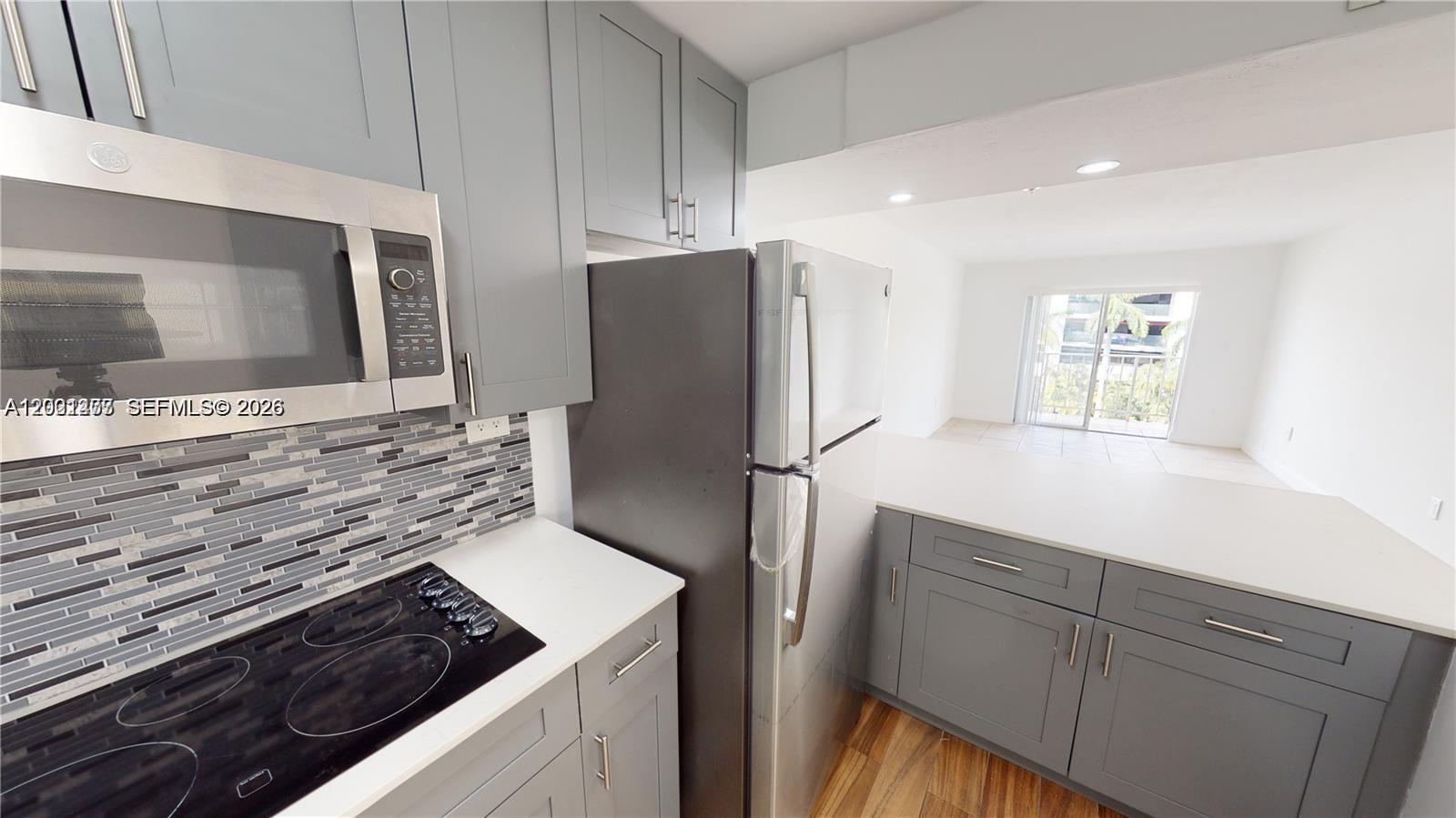 A kitchen features gray cabinets, stainless steel appliances, and a view into the living area — 453 SW 2nd St # 301C, Miami FL 33130, MIAMI, FL