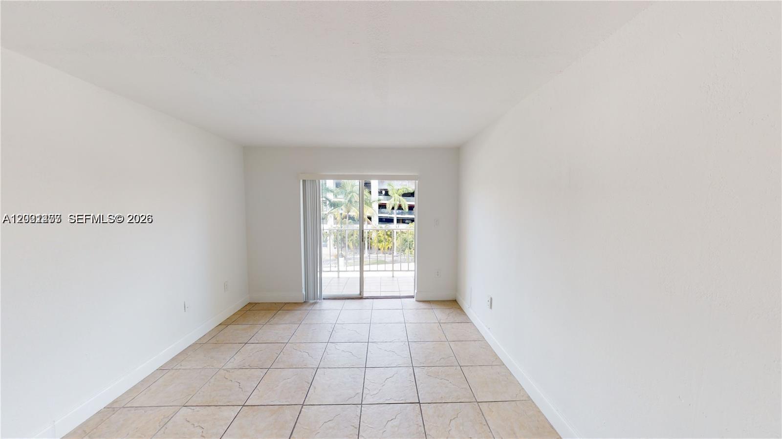 An empty room features white walls, beige tile flooring, and a sliding glass door to a balcony — 453 SW 2nd St # 301C, Miami FL 33130, MIAMI, FL