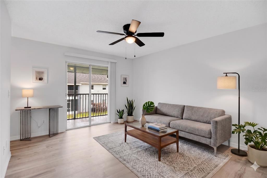 A living room features a gray sofa, a glass coffee table, and a sliding glass door — 4100 PERSHING POINTE PLACE UNIT 3, ORLANDO, FL