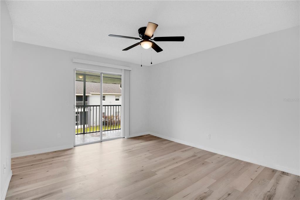 An empty room with light wood-look flooring, a ceiling fan, and a sliding glass door — 4100 PERSHING POINTE PLACE UNIT 3, ORLANDO, FL