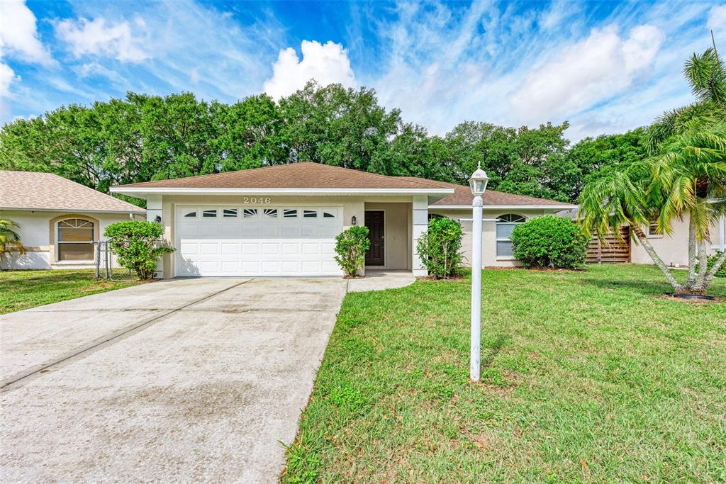 A single-story house with a white garage, a concrete driveway, and a front lawn — 2046 OLD TREVOR WAY, SARASOTA, FL