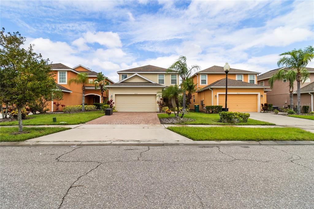 A street view of three suburban two-story houses with attached garages and paved driveways — 2615 SANTOSH COVE, KISSIMMEE, FL
