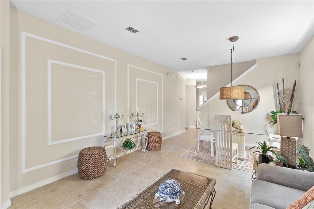 A dining area and living space feature tile floors, beige walls with molding, and furniture — 2615 SANTOSH COVE, KISSIMMEE, FL