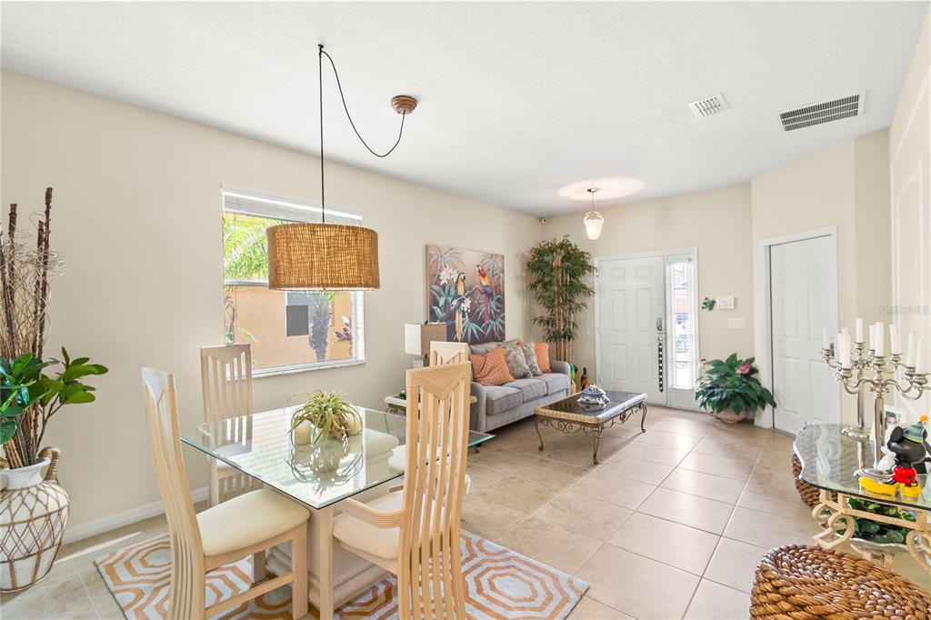 A dining area and living room with tile flooring, a glass table, and a sofa — 2615 SANTOSH COVE, KISSIMMEE, FL