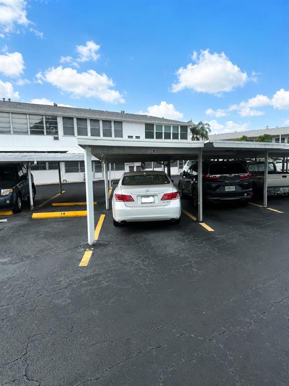 A white sedan is parked under a covered carport in an apartment complex parking lot — 5850 21ST STREET N UNIT 15, ST PETERSBURG, FL