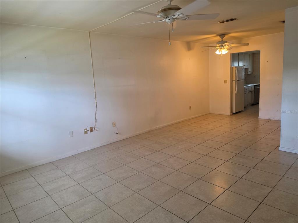 An open living area with light-colored floor tiles, white walls, and two ceiling fans — 5850 21ST STREET N UNIT 15, ST PETERSBURG, FL