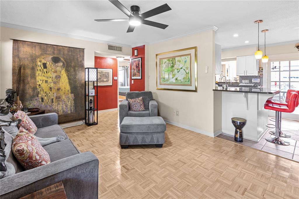 A living room with parquet flooring, a gray sofa, an armchair, and a kitchen counter — 2042 ISABELLE STREET, LARGO, FL