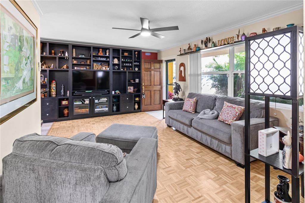 A living room features a large built-in entertainment center, gray sofa, and parquet wood flooring — 2042 ISABELLE STREET, LARGO, FL