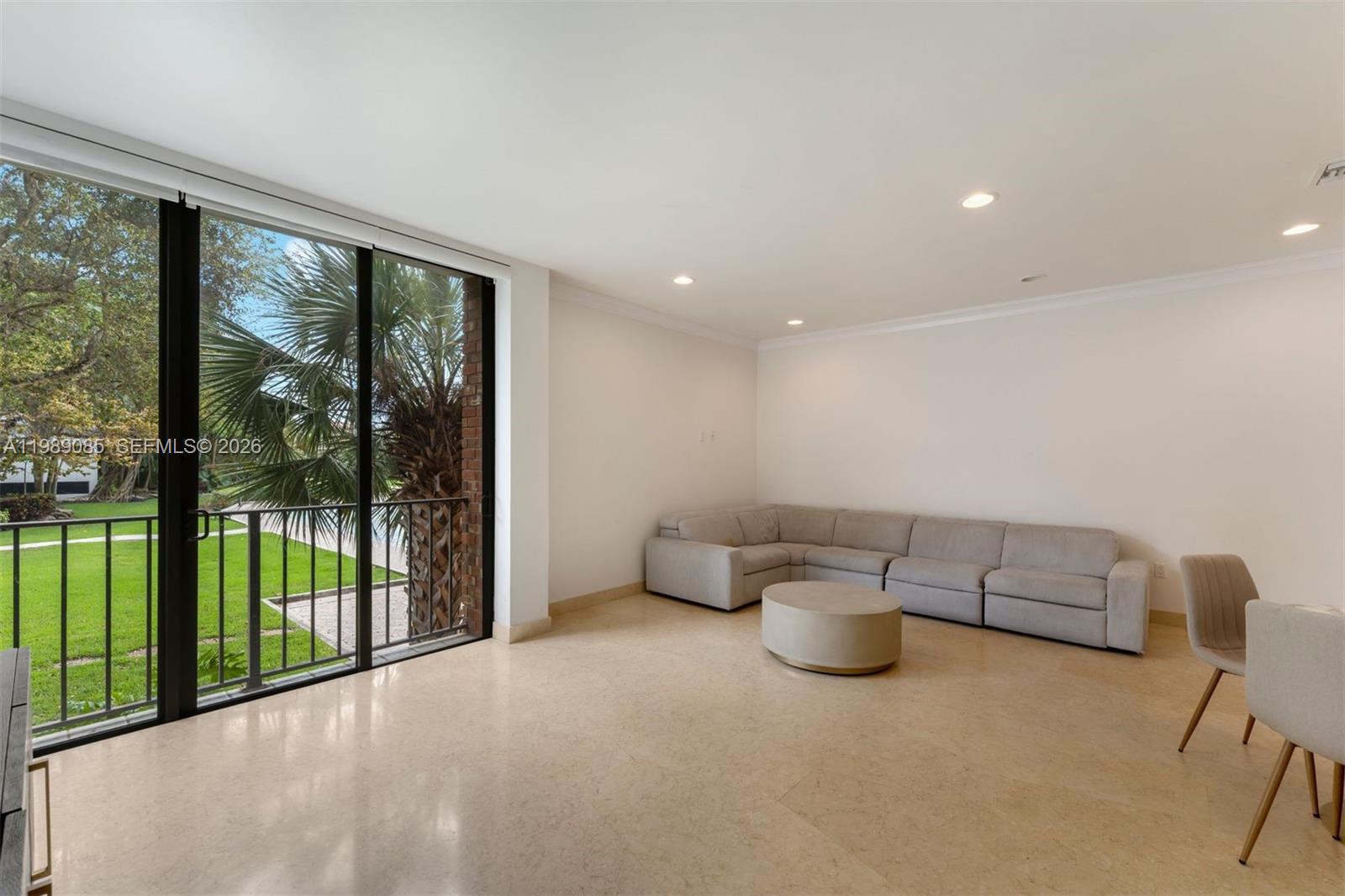 A living room with a beige sectional sofa, round coffee table, and sliding glass doors — 1566 NE Quayside Ter # D14, Miami FL 33138, MIAMI, FL