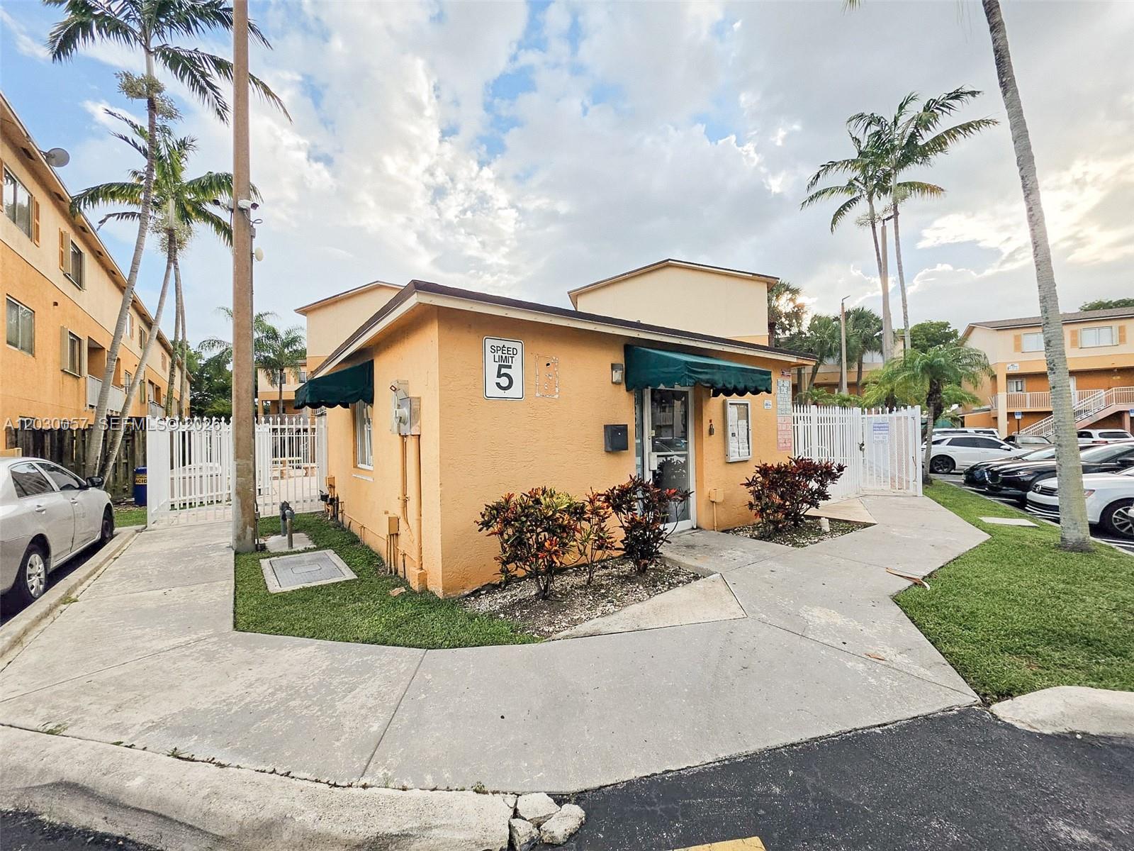 A small, peach-colored office building with a green awning stands near a sidewalk and palm trees — 6235 Kendale Lakes Cir # 236, Miami FL 33183, MIAMI, FL