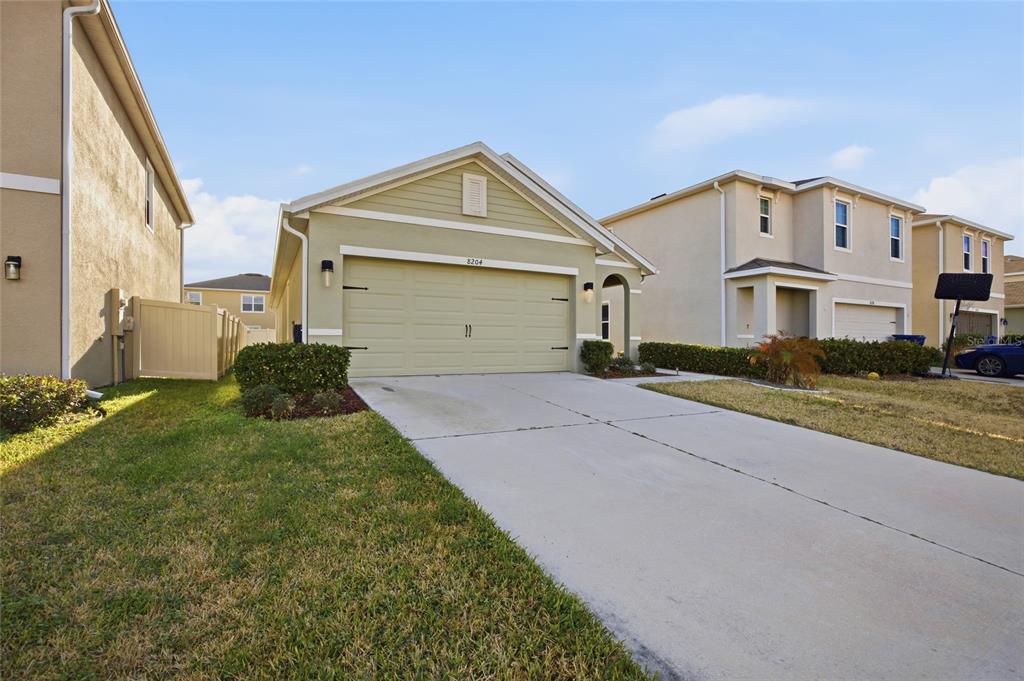 A light green single-story house with a two-car garage and a concrete driveway — 8204 PELICAN REED CIRCLE, WESLEY CHAPEL, FL