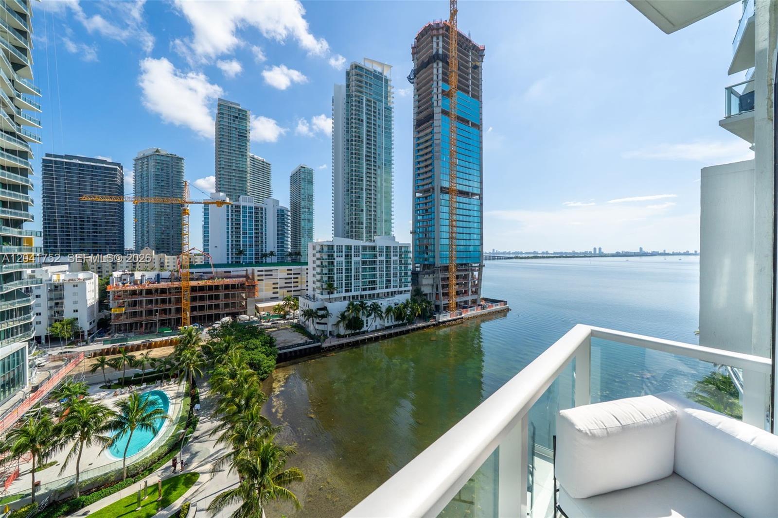 A balcony view overlooks a waterfront area with high-rise buildings and a swimming pool — 601 NE 27th St # 1001, Miami FL 33137, MIAMI, FL