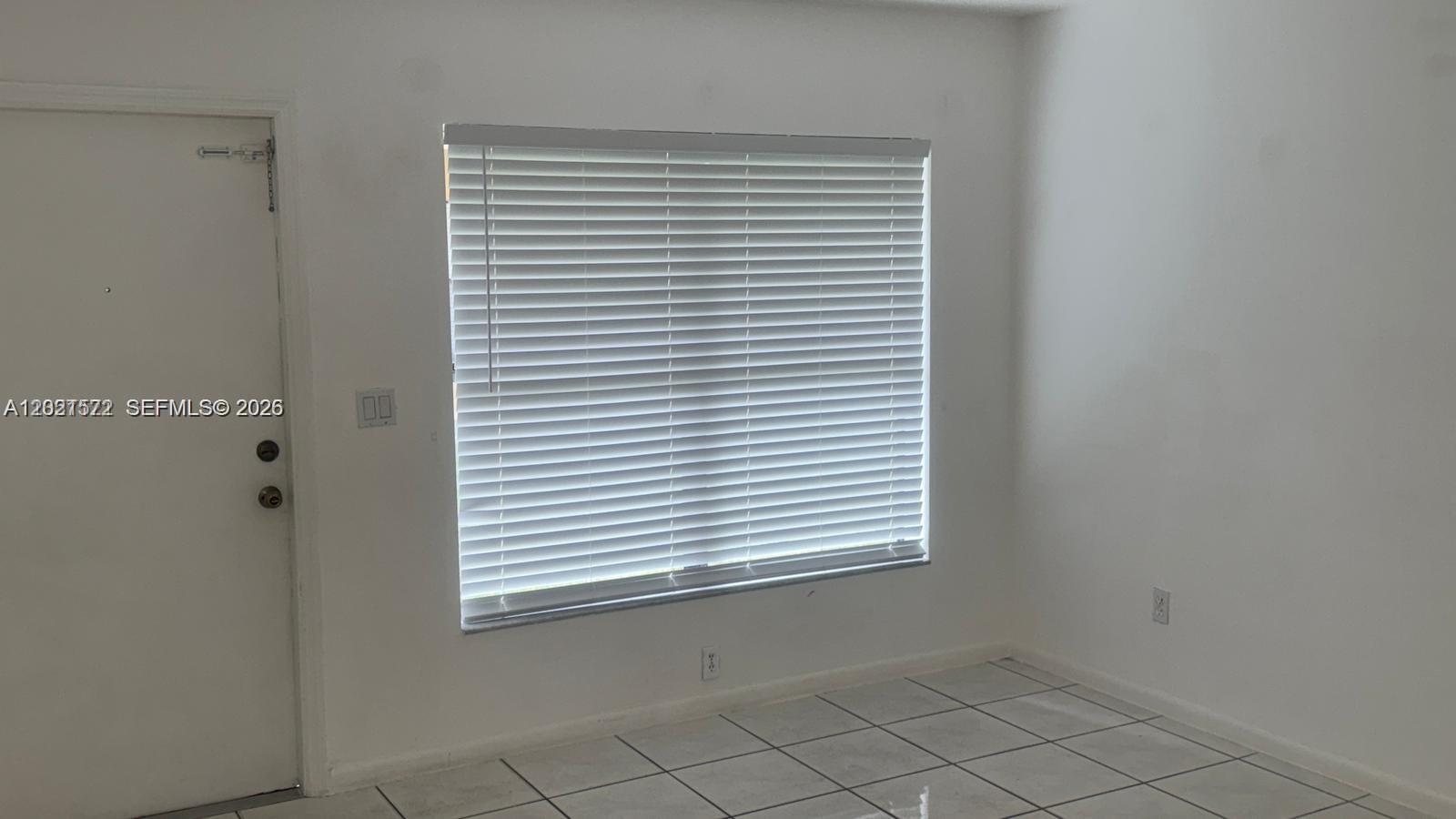 A room with white walls, tiled flooring, a single window with blinds, and a door — 2715 W 66th St # 21, Hialeah FL 33016, HIALEAH, FL
