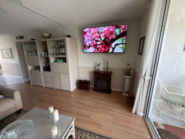 A living room features light wood flooring, a wall-mounted television, and a wooden display cabinet — 324 SE 10th Street # 207, Dania Beach FL 33004, DANIA BEACH, FL