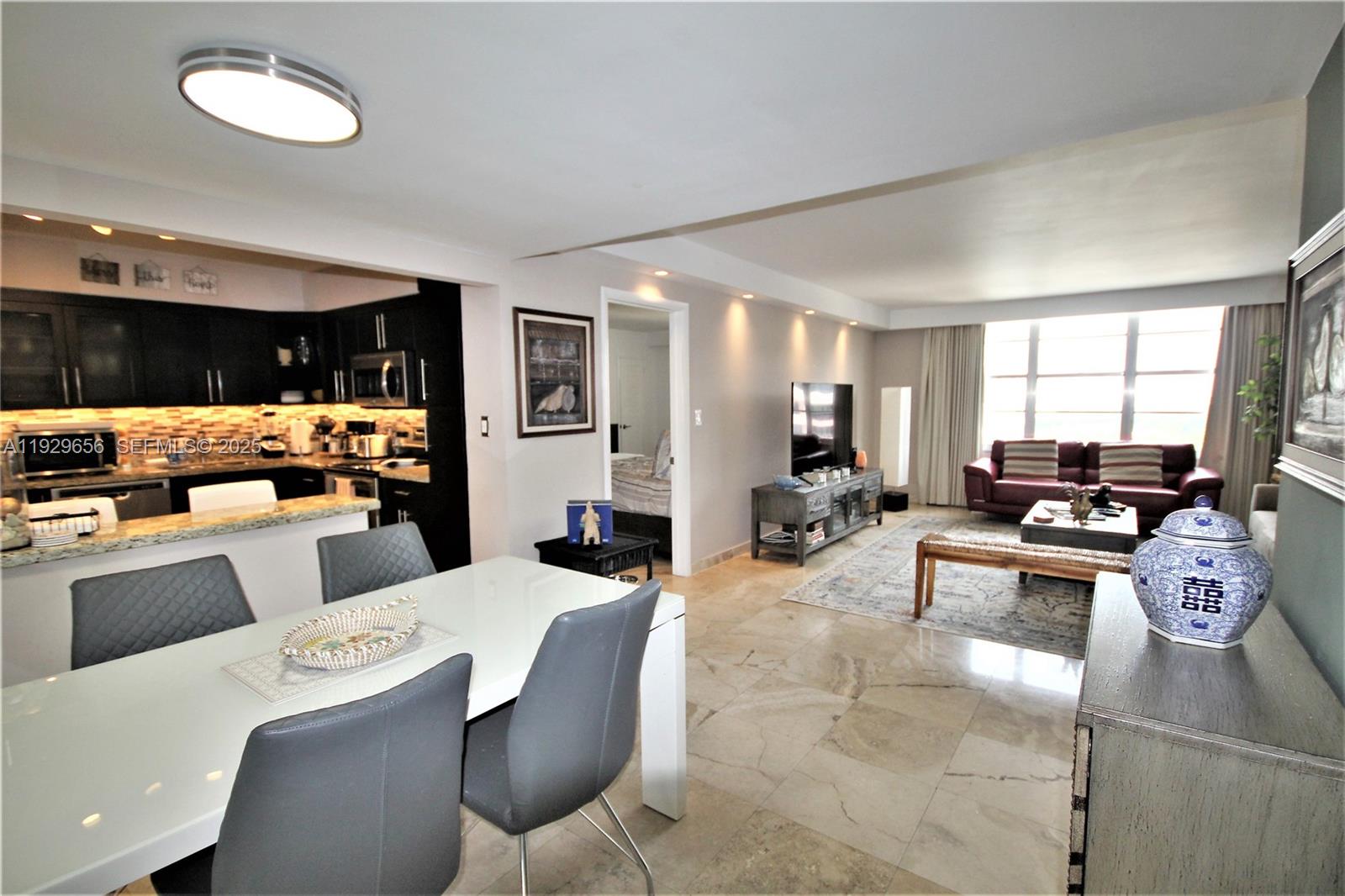 An open-concept living and dining area features tile floors, dark kitchen cabinets, and modern furniture — 5161 Collins Ave # 1610, Miami Beach FL 33140, MIAMI BEACH, FL