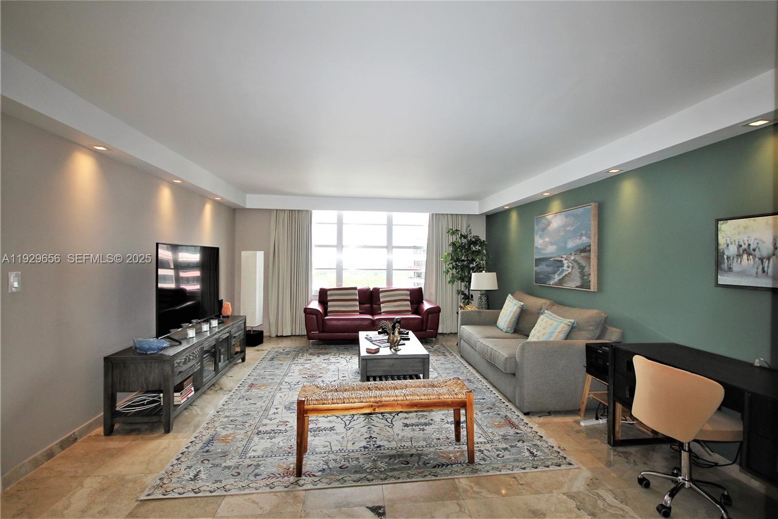 A living room features a green accent wall, a grey sofa, a red loveseat, and tile flooring — 5161 Collins Ave # 1610, Miami Beach FL 33140, MIAMI BEACH, FL
