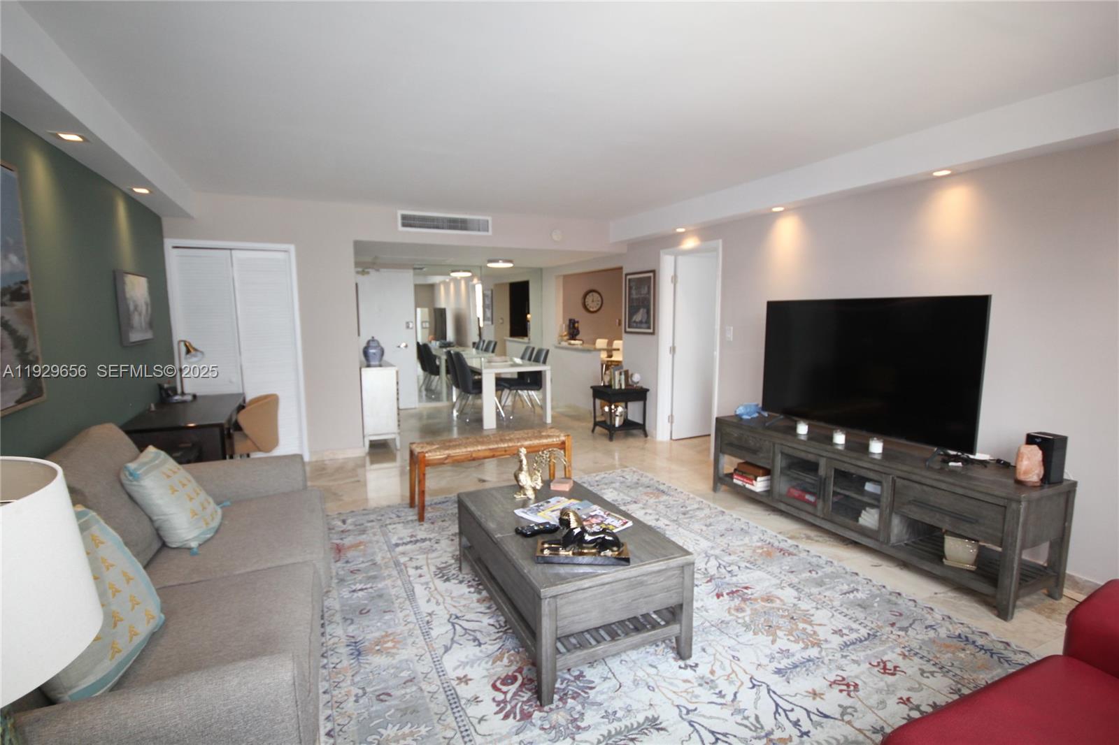 A living room features a grey sofa, a coffee table, and a large television console — 5161 Collins Ave # 1610, Miami Beach FL 33140, MIAMI BEACH, FL