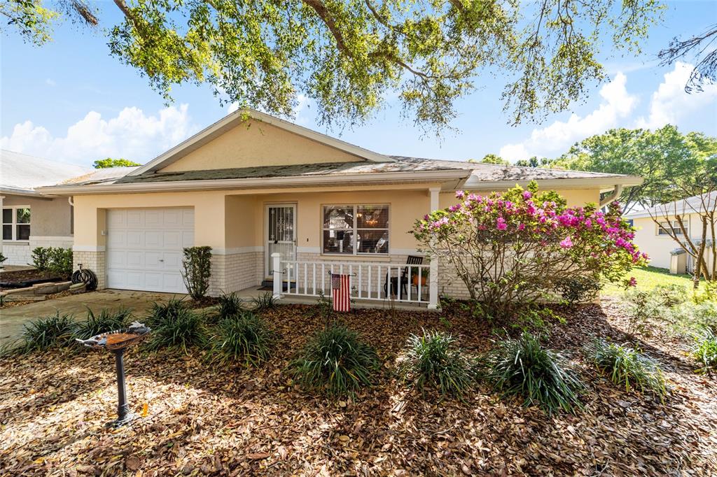 A single-story house with a white garage, a front porch, and a flowering bush — 9725 SW 94 TERRACE UNIT C, OCALA, FL