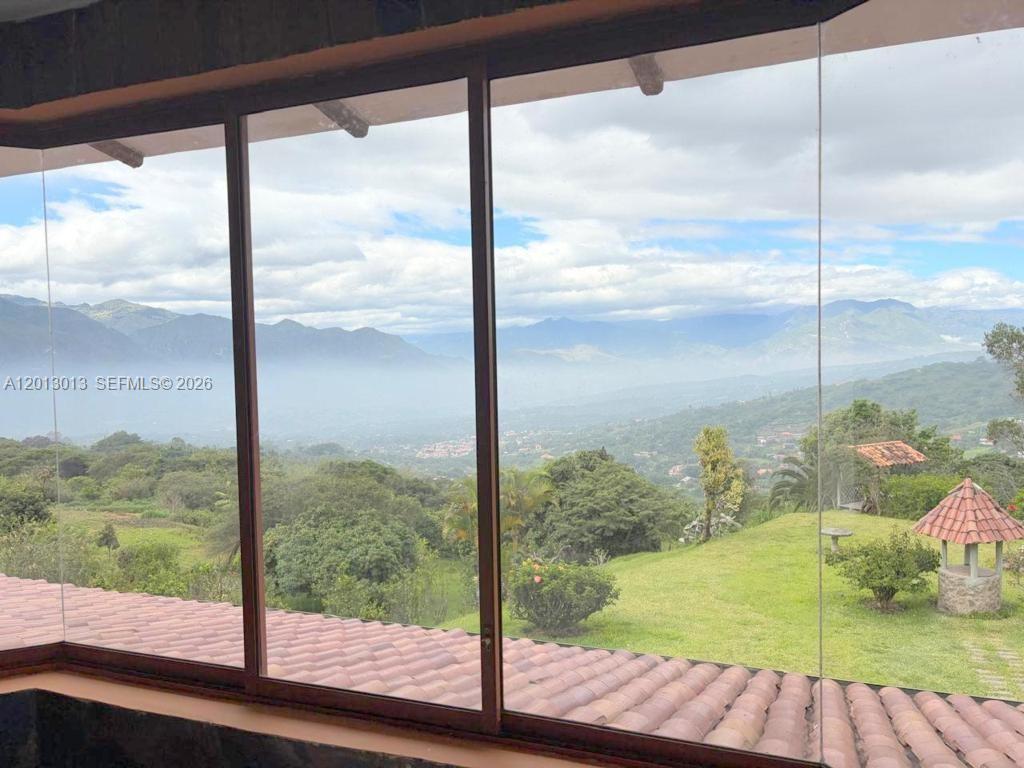 A view of a mountain landscape through large glass windows above a tiled roof — NA Via Guadaleg, FL