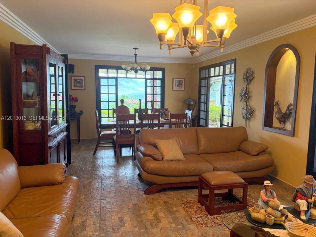 A living room with leather sofas, a dining area, and a large chandelier — NA Via Guadaleg, FL