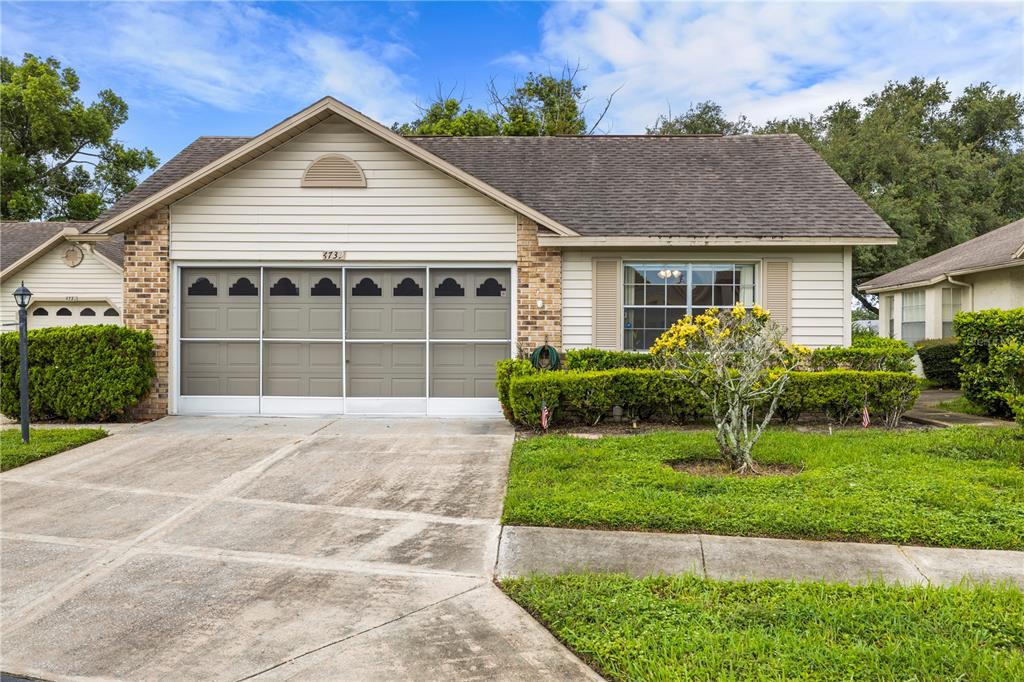 A single-story house with a beige siding facade, a two-car garage, and a front lawn — 4739 CARRINGTON COURT, NEW PORT RICHEY, FL