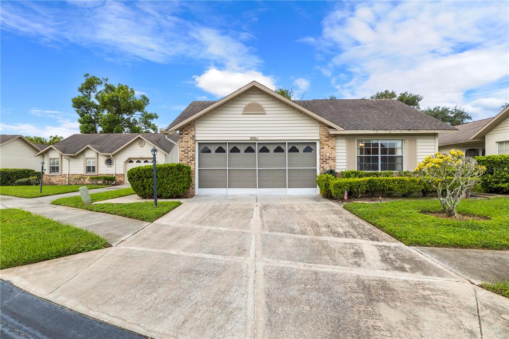 A single-story house with a beige facade, a two-car garage, and a concrete driveway — 4739 CARRINGTON COURT, NEW PORT RICHEY, FL
