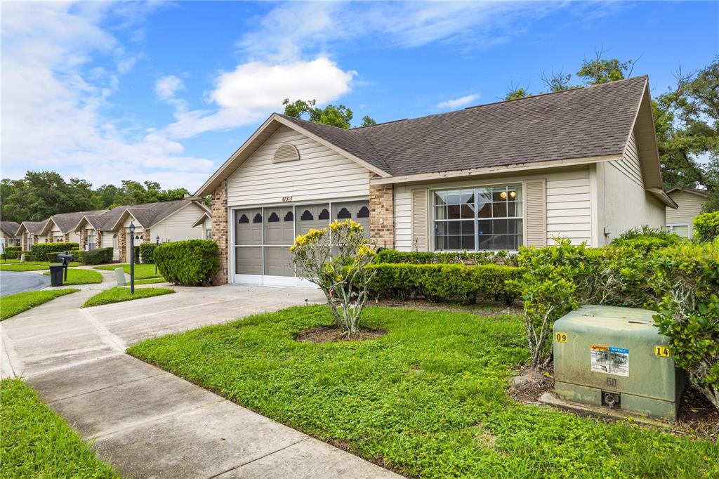A single-story house with beige siding, a garage, and a green utility box in front — 4739 CARRINGTON COURT, NEW PORT RICHEY, FL
