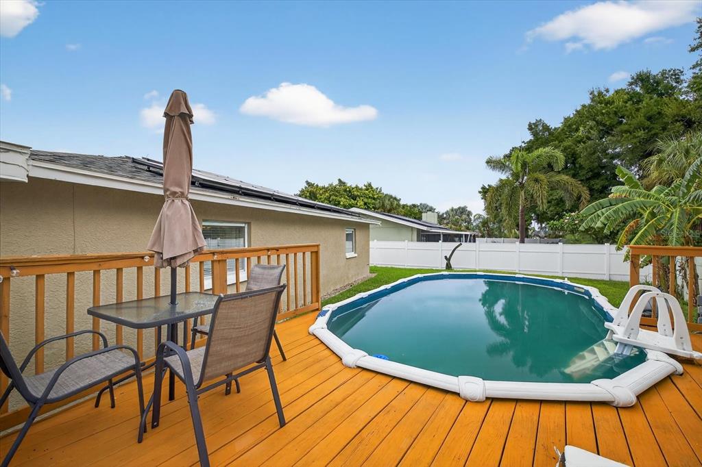 A wooden deck features a patio table with chairs and an above-ground swimming pool — 420 LEWIS BOULEVARD SE, ST PETERSBURG, FL