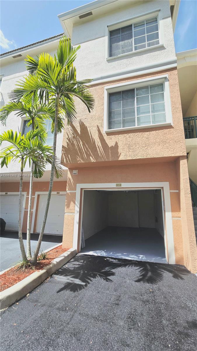 A three-story townhouse exterior features a ground-level open garage and two upper floors with windows — 1307 E Myrtlewood Cir E # 1307, Palm Beach Gardens FL 33418, PALM BEACH GARDENS, FL