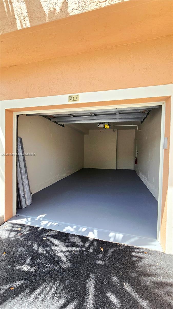 An empty garage with a gray painted floor and a fire extinguisher on the wall — 1307 E Myrtlewood Cir E # 1307, Palm Beach Gardens FL 33418, PALM BEACH GARDENS, FL