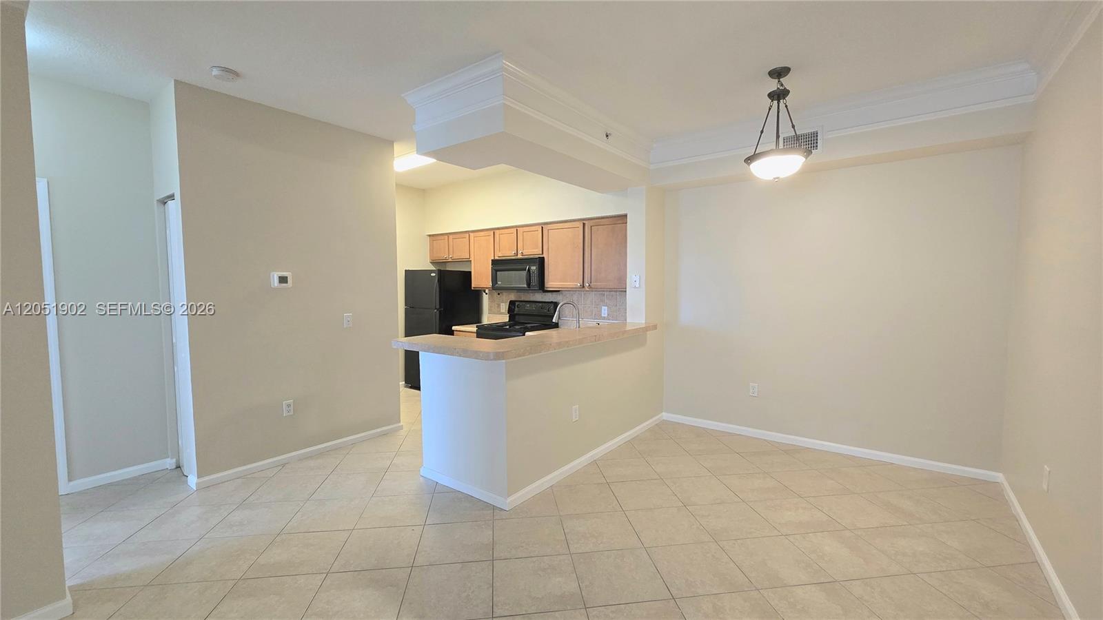 A kitchen with light wood cabinets and a breakfast bar overlooks an open dining area — 1307 E Myrtlewood Cir E # 1307, Palm Beach Gardens FL 33418, PALM BEACH GARDENS, FL