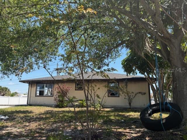 A single-story house with light-colored siding is viewed from a yard with a tire swing — 3538 PINETREE STREET, PORT CHARLOTTE, FL
