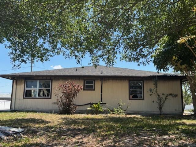 The exterior of a single-story house with light-colored siding, a dark roof, and broken windows — 3538 PINETREE STREET, PORT CHARLOTTE, FL
