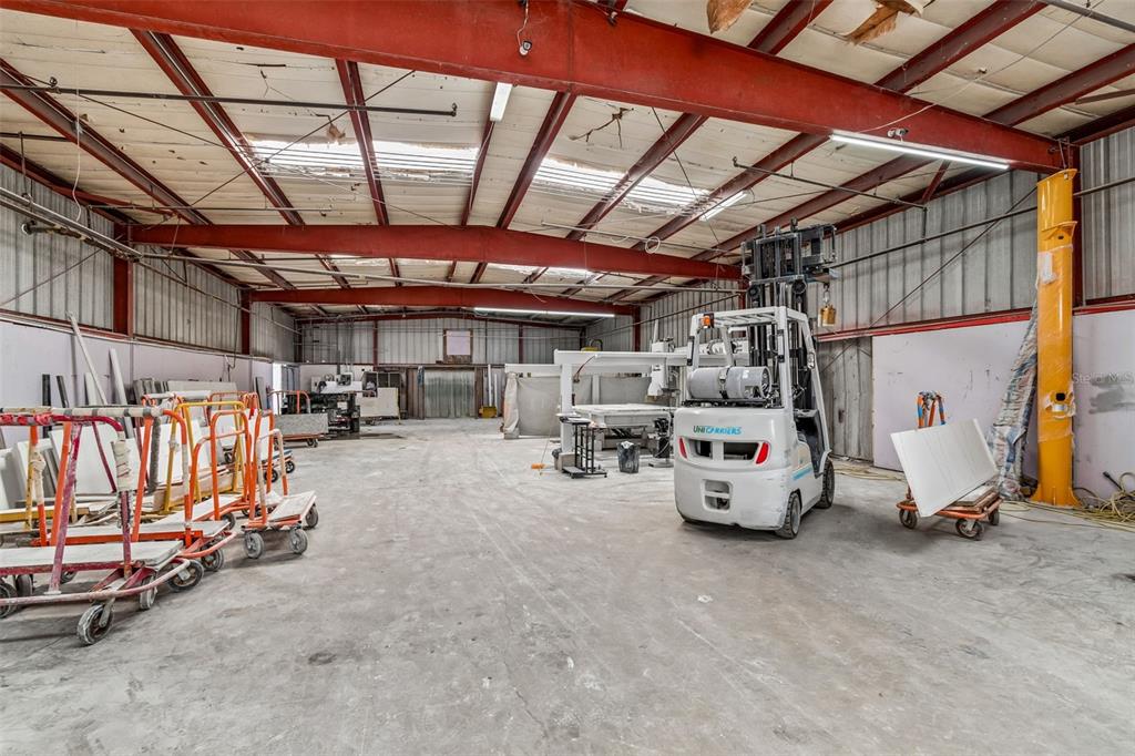 A large industrial warehouse space features a concrete floor, red steel beams, and a forklift — 4214 W VIRGINIA AVE UNIT 10-A, TAMPA, FL