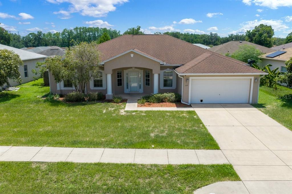 A single-story suburban house features a tan exterior, a two-car garage, and a front porch — 3024 NE 27TH STREET, OCALA, FL