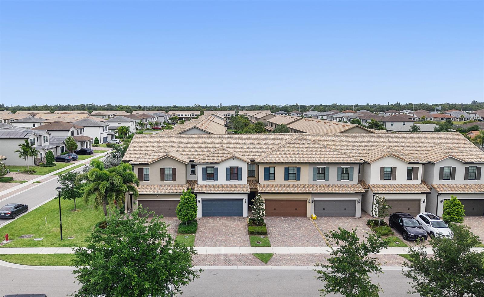 An aerial view shows a row of multi-story townhomes with tiled roofs and paved driveways — 4846 San Fratello Circle, FL 33467, FL