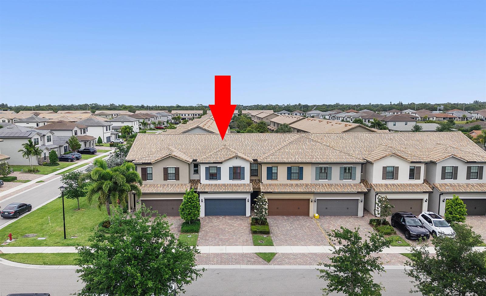 An aerial view of a multi-unit townhouse complex with a red arrow pointing to one unit — 4846 San Fratello Circle, FL 33467, FL
