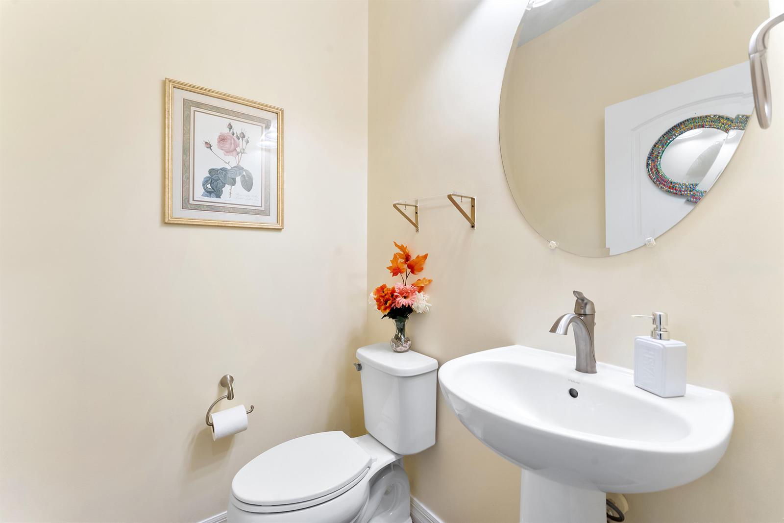 A small bathroom features a pedestal sink, a toilet, and a round wall mirror — 4846 San Fratello Circle, FL 33467, FL