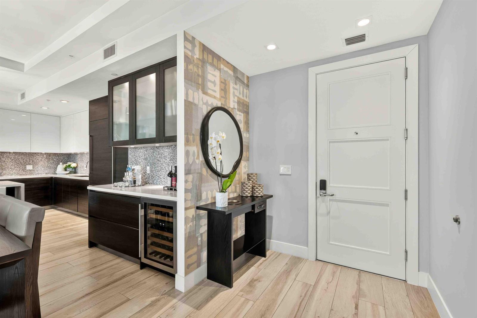 A modern entryway features a patterned accent wall, a console table, and a wine fridge — 155 E Boca Raton Road # 611, Boca Raton FL 33432, BOCA RATON, FL