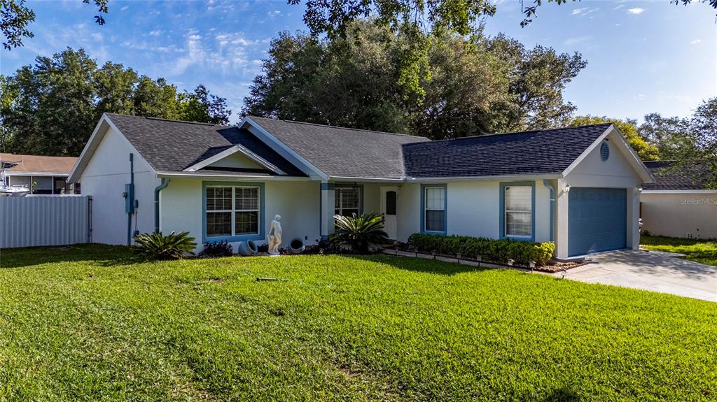 A single-story house with a white exterior, dark roof, and attached garage sits on grass — 10618 REAGANS RUN DRIVE, CLERMONT, FL