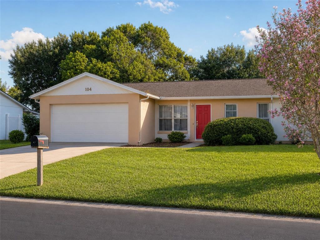 A single-story house with a tan exterior, a red front door, and a two-car garage — 104 MORELIA LANE, KISSIMMEE, FL