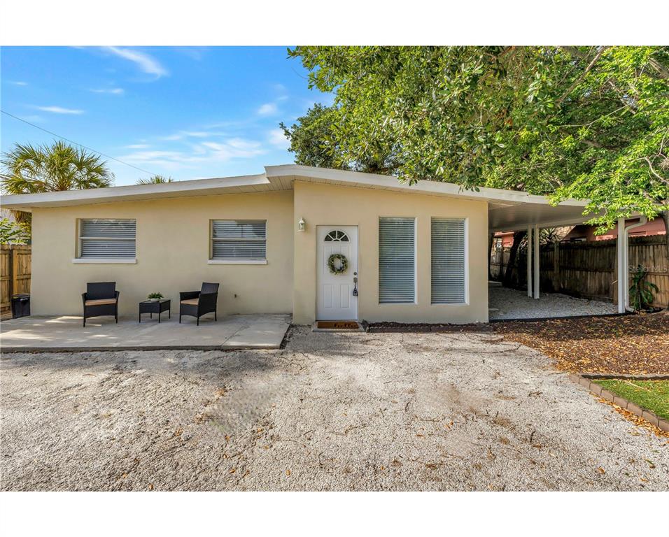 A single-story house with a gravel driveway, a patio, and a covered carport — 110 NE MONROE CIRCLE N UNIT 1, ST PETERSBURG, FL