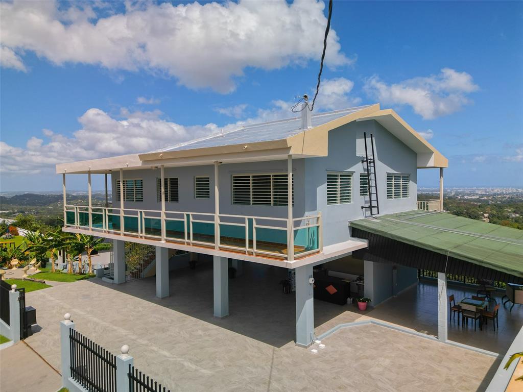 An elevated two-story house with a balcony, metal roof, and a large paved ground-level patio — LOT 5-A HOLLYWOOD UNIT 5-A, SAN JUAN, PR