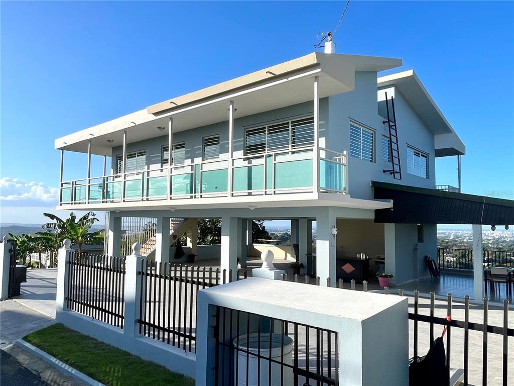 A two-story house with a wrap-around balcony stands behind a black metal fence — LOT 5-A HOLLYWOOD UNIT 5-A, SAN JUAN, PR