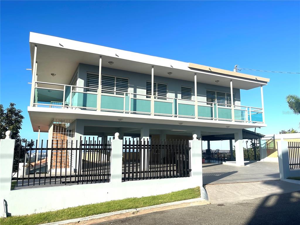 A two-story house with a large balcony, glass railings, and a ground-level carport — LOT 5-A HOLLYWOOD UNIT 5-A, SAN JUAN, PR