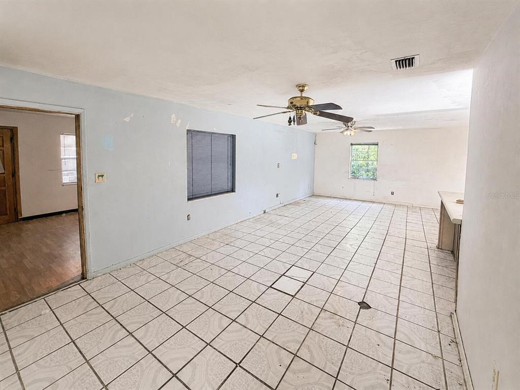An empty room with light blue walls, white tiled floors, and two ceiling fans — 6806 SE 215TH STREET, HAWTHORNE, FL