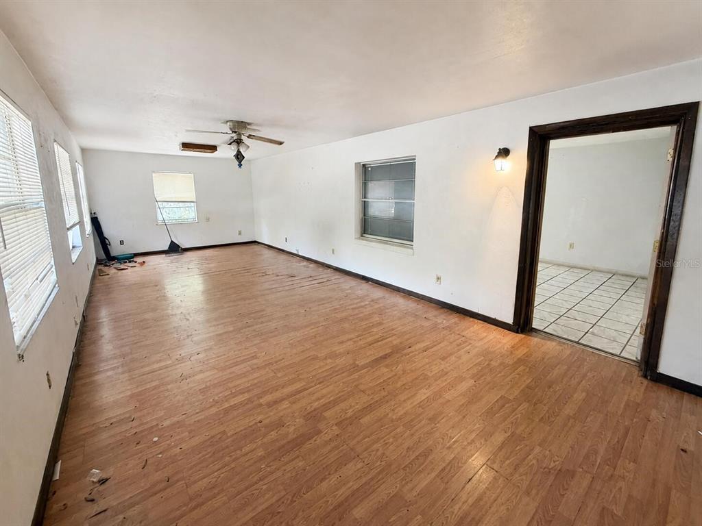 An empty room with wood-look flooring, white walls, a ceiling fan, and a doorway — 6806 SE 215TH STREET, HAWTHORNE, FL