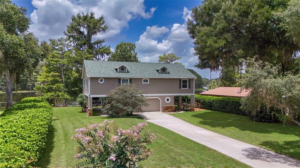 A two-story house with a raised foundation and a driveway sits on a grassy lot — 6610 S MERLEING LOOP, FLORAL CITY, FL