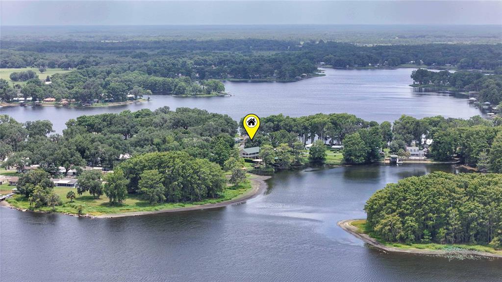 An aerial view shows a house nestled among trees on a point of land — 6610 S MERLEING LOOP, FLORAL CITY, FL