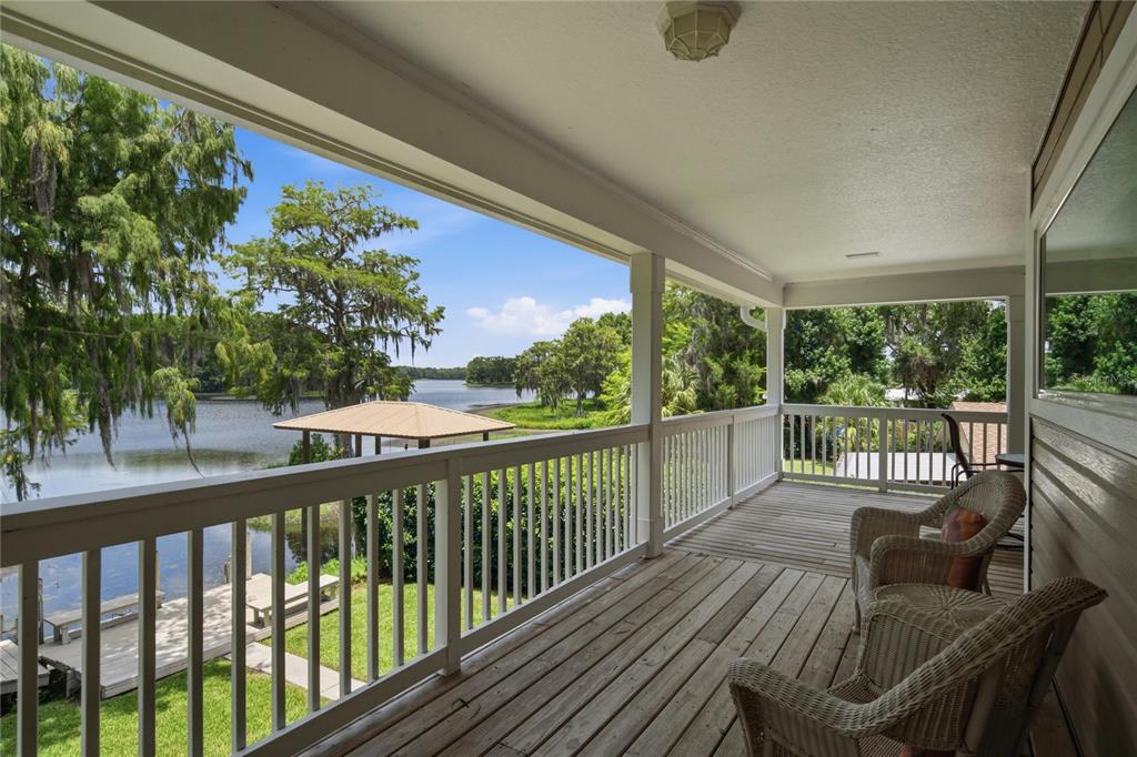 A covered wooden deck overlooks a lake with a dock and a gazebo — 6610 S MERLEING LOOP, FLORAL CITY, FL